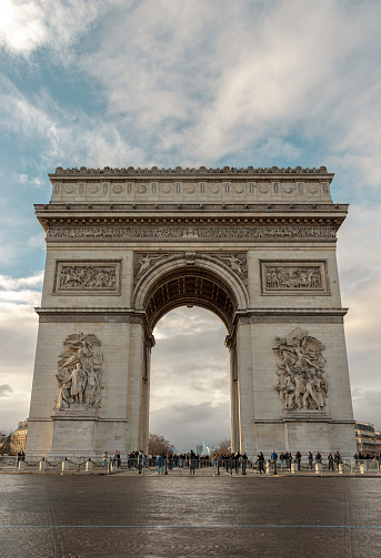 France, Paris - Jan 03, 2024 - Famous Arc de Triomphe (Triumphal Arch) at the city center of Paris and traffic trails in Chaps Elysees. Symbol of the glory and historical heritage, Iconic touristic architectural landmark, Tourism and travel concept, Space for text, Selective focus.