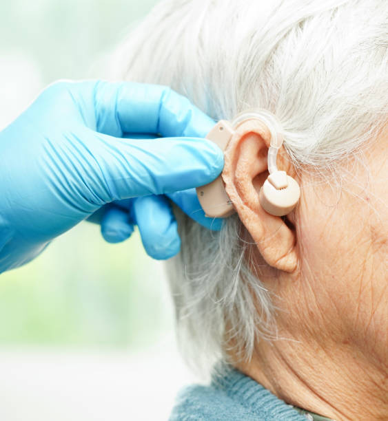 istock Doctor install hearing aid on senior patient ear to reduce hearing loss problem. 1964239852