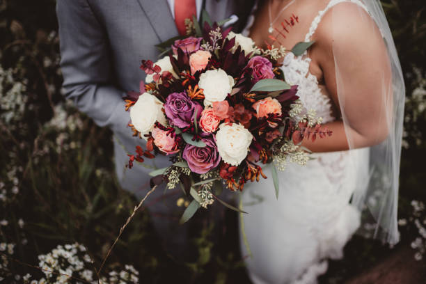istock Bride and groom holding brightly colored wedding flowers 1964253486