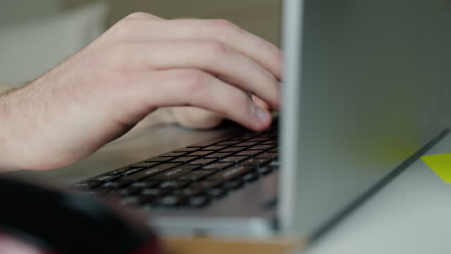Male hands typing on laptop keyboard.