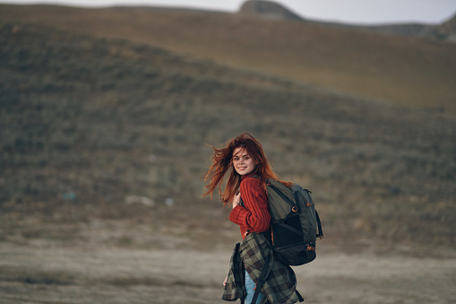 woman in a red sweater and jeans with a backpack on her back are resting in the mountains in nature. High quality photo