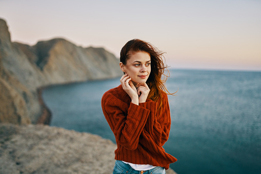 woman in a red sweater in the mountains near the sea travel tourism model. High quality photo