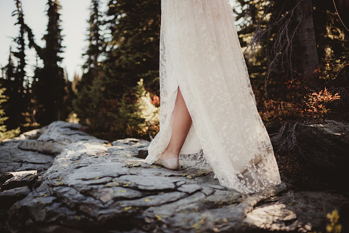Bride walking on rock through the forest for wedding