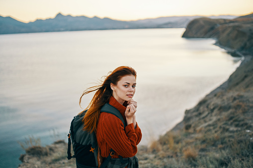 traveler with a backpack in a sweater outdoors in the mountains near the sea side view Copy Space. High quality photo