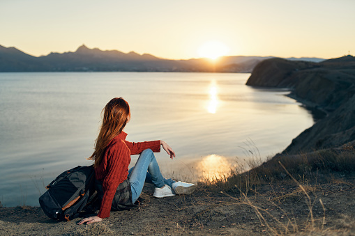 woman sits on the ground in nature in the mountains near the sea adventure sunset. High quality photo