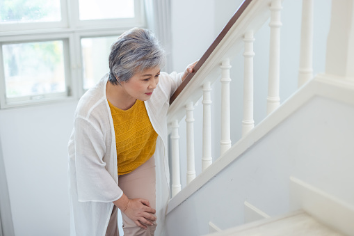 Asian elderly woman walking up stairs have pain knee ache in house. old woman went up stairs. Female old people leg pain and inflammation. Grandmother home alone.