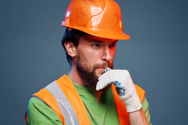 istock Man in work uniform orange paint safety work fatigue blue background 1964335548