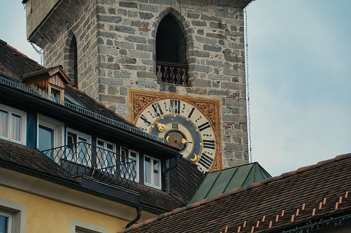 Brunico, Italy – September 13, 2023: A towering clock structure adjacent to a slope-side building