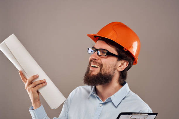 istock Male engineer with glasses in orange paint. Professional blueprints in hands 1964344572