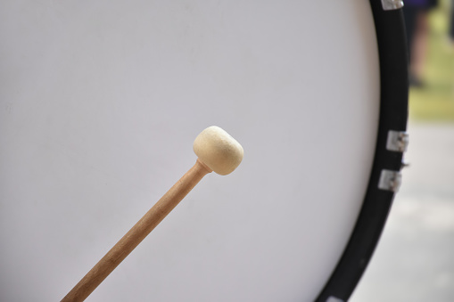 Marching bass drum, snare drum and marching mallets holding in hands.