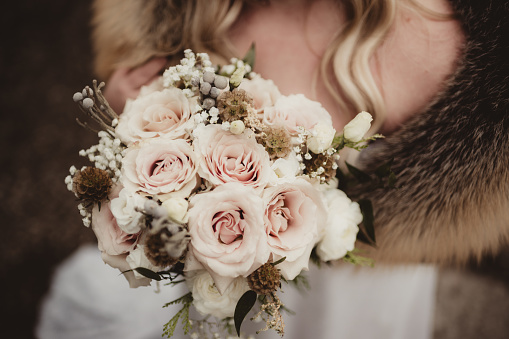 Bride holding bouquet of pink roses in the winter