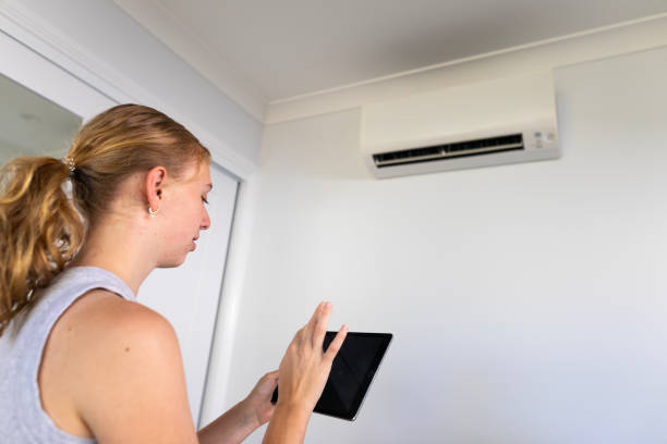 istock Young woman controlling an air conditioner with a tablet computer 1964391901