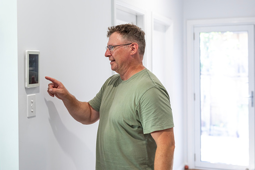 Man using an automated home heat and cooling control. Lismore, NSW, Australia