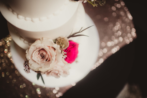 Wedding cake with couple figurines and flowers against white background