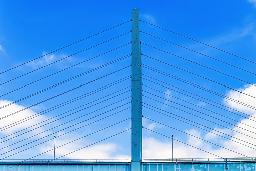 Road bridge pylon with cables at a blue sky