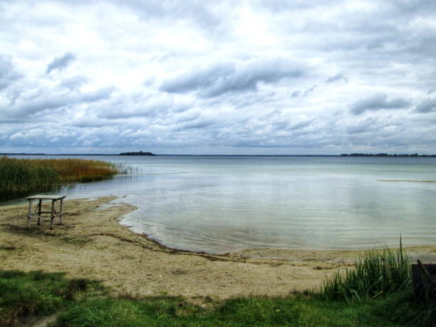 Tranquil autumn scene on the lake shore with overcast skies and calm water
