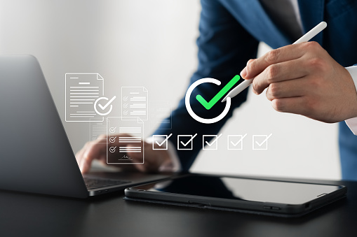 Business performance checklist, male businessman using laptop and tablet doing evaluation Online survey questionnaires, digital form checklists.