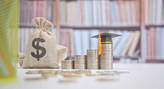 Student loan and financial decision-making, financial literacy concept : Graduation cap, dollar bag, coins on a table. Financial literacy is the ability to understand and make use of financial skills.