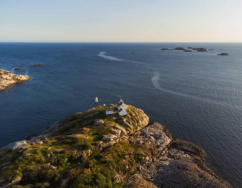 The lighhouse from the small fishing town of Henningsvær, Lofoten, Norway at sunset, from a drone point of view. Clear blue sky and crisp colors. Drone point of view, late summer.