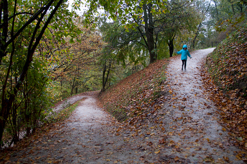 Boy with Blue Waterproof Jacket Runs on the Mountain Path During a Rainy Autumn Day. Ljubljana, Slovenia