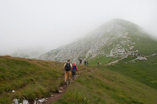 Hikers on the Mount Arera Path During a Cloudy Summer Day. Zambla Alta Village, Bergamo Alps, Italy