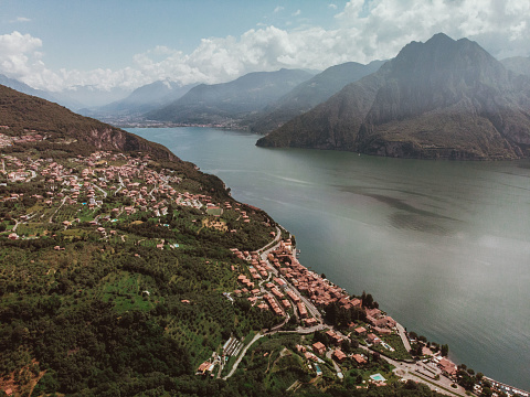 Breathtaking panoramic view of a lake with mountains seen from the top of a peak during a trekking day in summer. In the background the houses of a town on the shores of Lake Iseo in Lombardy