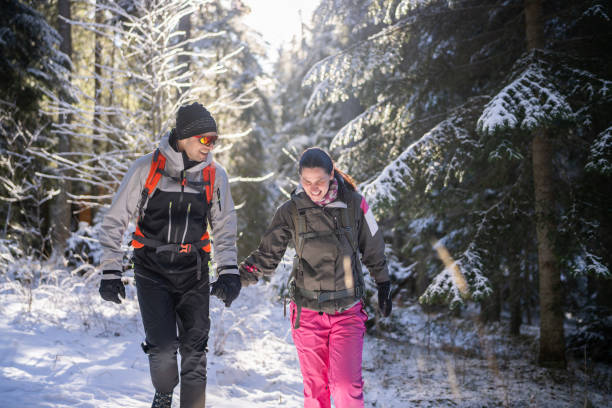 istock Happy couple walking through snowy woods 1964632198