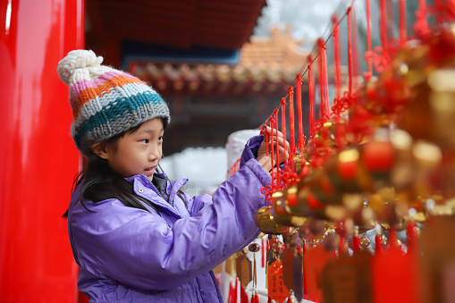 An Asian girl goes to the temple to pray before the Lunar New Year. She writes her wishes on a sky lantern and hangs the sky lantern on the tree with a red Chinese knot. This is a traditional Chinese custom during the Lunar New Year.