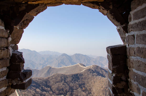 old brick window of a fragment of the chinese wall. view from an ancient window of the misty mountains of the chinese great wall - chinese wall foto e immagini stock