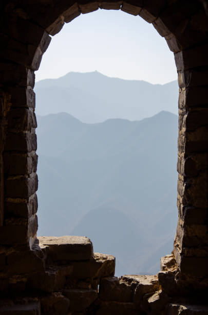 old brick window of a fragment of the chinese wall. view from an ancient window of the misty mountains of the chinese great wall - chinese wall foto e immagini stock