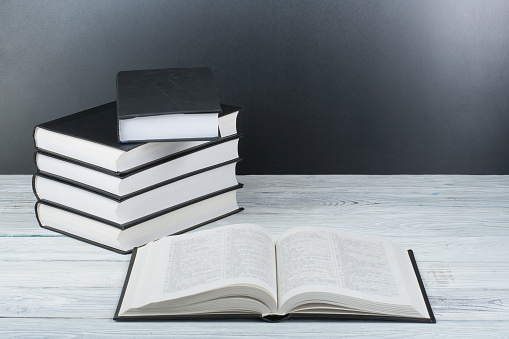 Open black and Whitel books on wooden table, black board background. Back to school. Education business concept