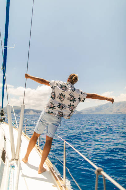istock Young handsome man standing on a sailboat deck 1964708645