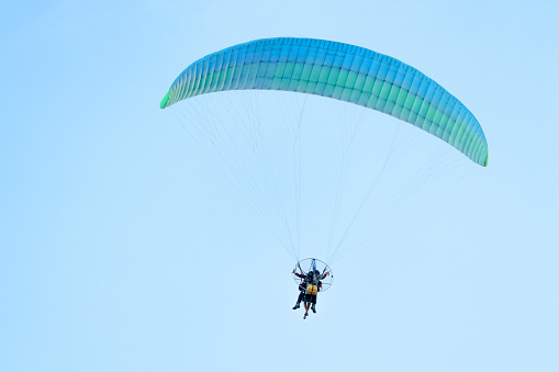 Paramotor pilot and his tourist client flying in the sky