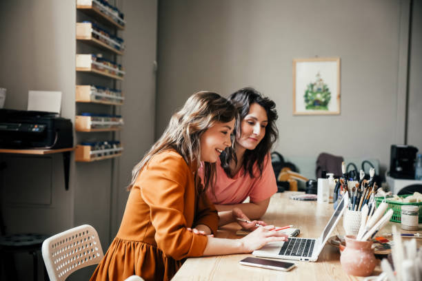 Two attractive young female employees discussing their business in workshop Business discussion. Two attractive young female employees discussing their small business in the workshop. small business stock pictures, royalty-free photos & images