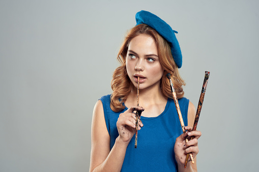 woman artist brush in hand blue beret dress hobby art lifestyle light background. High quality photo