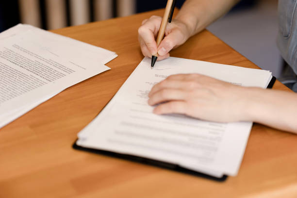 istock Female hands signing documents, wooden table in office. 1964769949