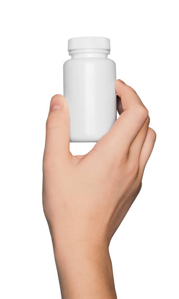 istock Hand holding white jar for vitamins, capsules, nutritional supplements, isolated on a white background. 1964795267