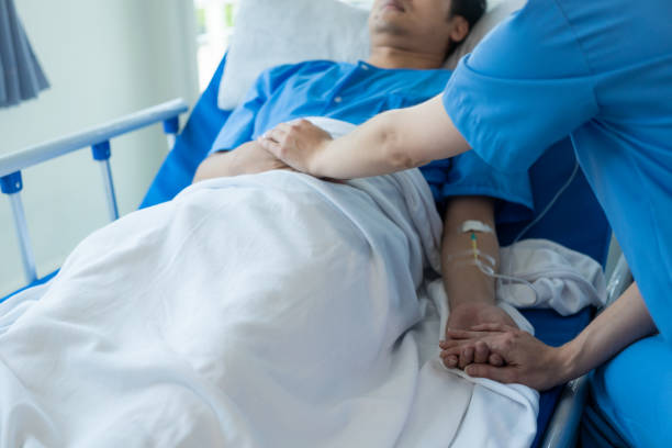 istock Young Asian male patient lying in bed while checking his pulse. Consult and explain with the nurse who takes notes and assists in the hospital in the recovery room in the hospital department. 1964814966