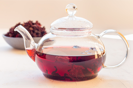 Red tea karkade or hibiscus in a glass tea pot and on plate, horizontal