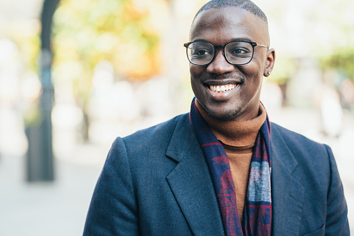 Shot of handsome african-american young man outdoors in the city. Portrait of a young African-American businessman looking away and smiling