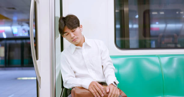 portrait asian businessman wearing earbuds feel sleepy while sitting commuting on metro mrt car