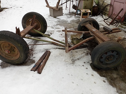 Repair of a metal cart on rubber automobile wheels. Car maintenance in winter. Design and elements of horse transport.