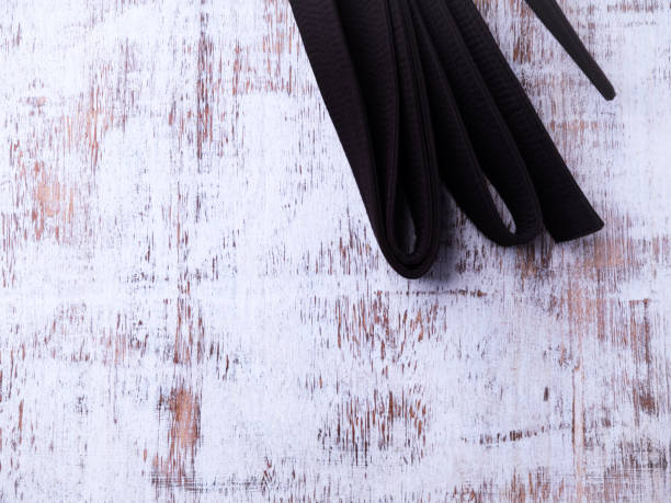 Black karate belt on rustic wooden background. Top view.