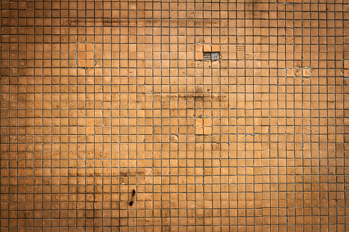 Close-up on a wall made up of small brown tiles.