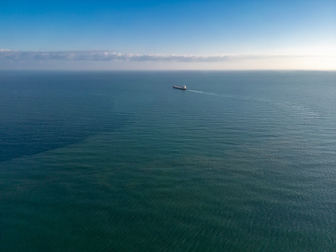 Aerial drone view above sea port. Cargo vessel is loading containers and bulk. Professional business logistics and transportation of Ro-ro ship.