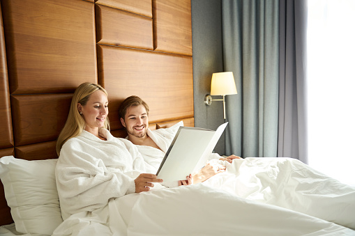 Awoke newlyweds study the menu in bed, the couple chooses breakfast in the room