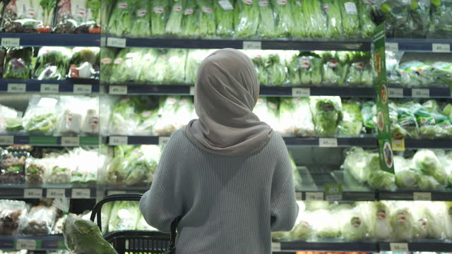 Rear View Of Muslim Woman Picking Food From Refrigerated Section In Supermarket