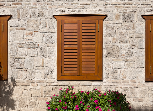 Closed brown wooden shutters on a white wall background