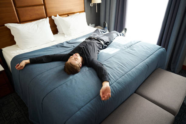 istock Guy lies with his arms outstretched on a large bed 1964918060