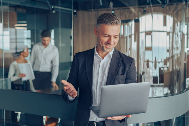 Handsome businessman talking via video call with client use laptop while standing in office